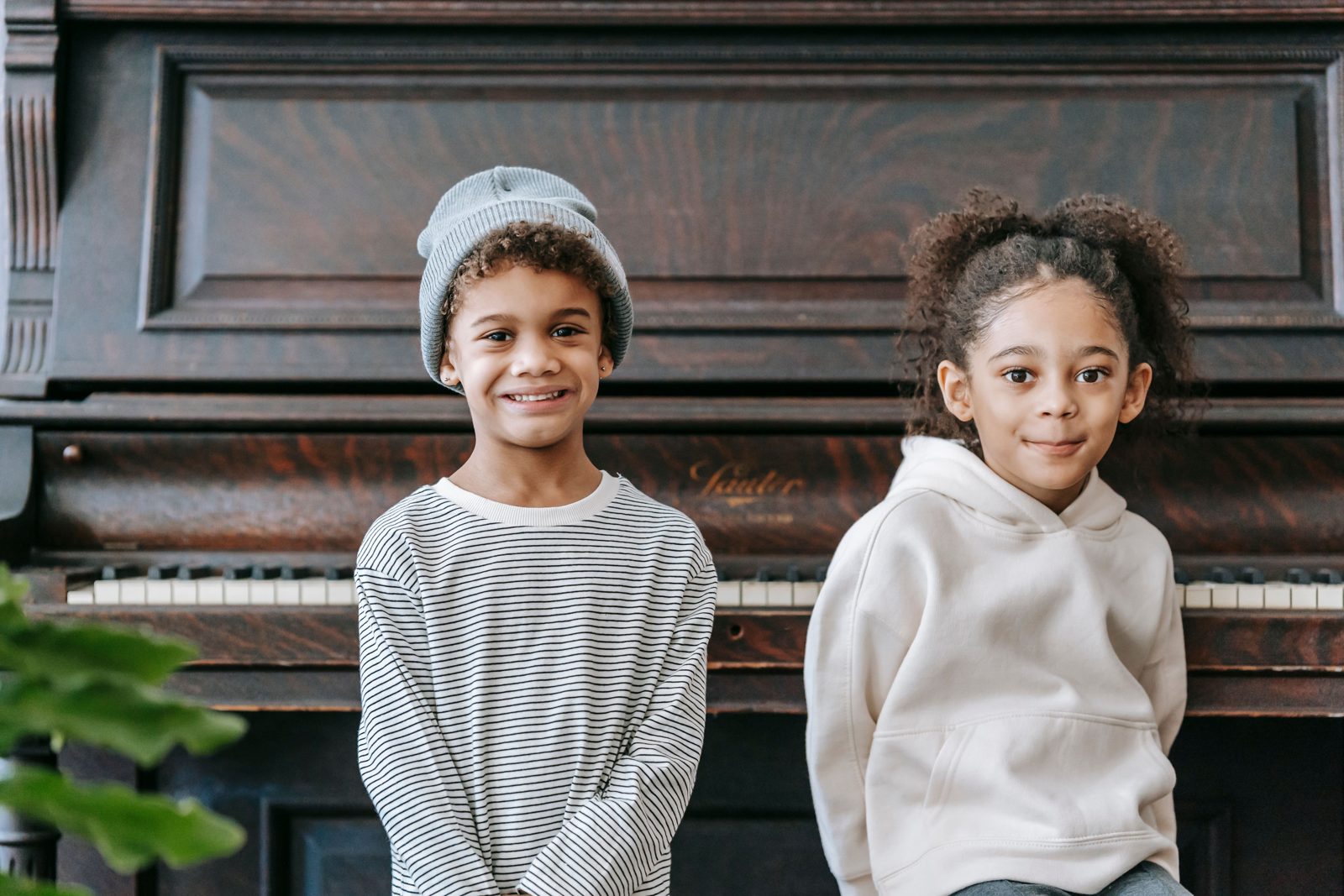 Deux enfants souriants devant un piano